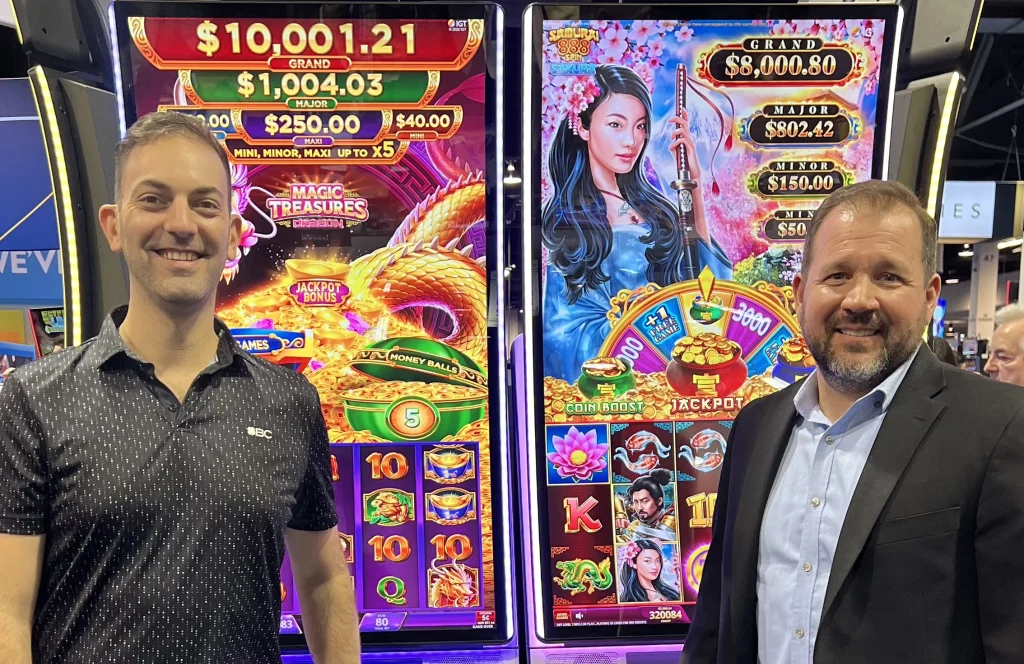 Brian Christopher stands with Chris Carlisle at a bank of machines during IGA 2024.