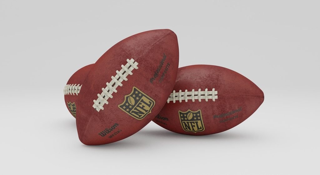Two footballs in front of a white backdrop 