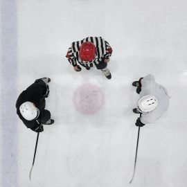 Two hockey players and referee in the ice rink