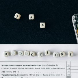 Tax deduction spelled in beads, a calculator and a tax document.