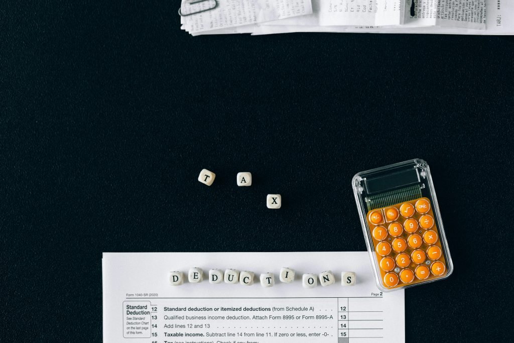 Tax deduction spelled in beads, a calculator and a tax document.