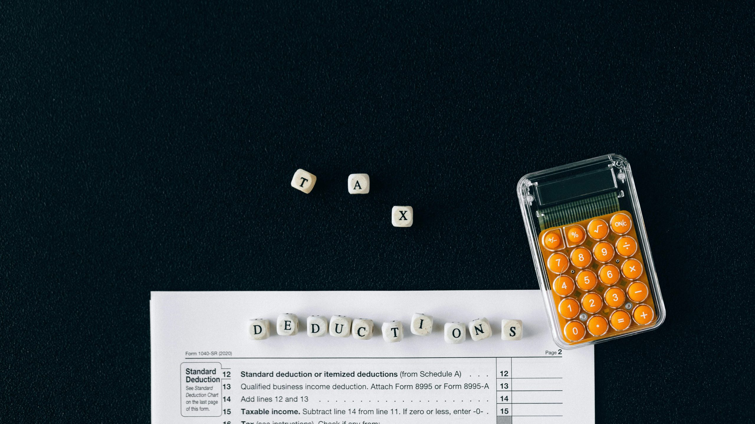 Tax deduction spelled in beads, a calculator and a tax document.